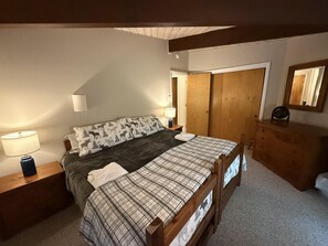 A bedroom with a bed, bedside tables, a dresser, a mirror, and a door. - Ski Condo in Lincoln next to Loon Mountain! (Lincoln)