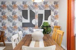 A dining area with a wooden table, white chairs, and a large white vase.