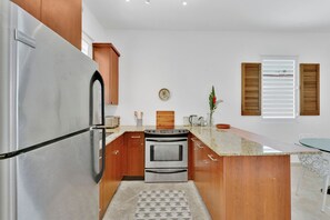 Una cocina con refrigerador de acero inoxidable, armarios de madera, horno empotrado y encimera de granito.