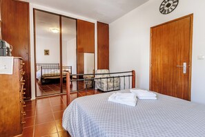 Une chambre à coucher avec un lit, une chaise, une armoire et un miroir.