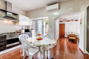 Une cuisine avec des meubles blancs, un fourneau et un coin repas comprenant une table et des chaises.