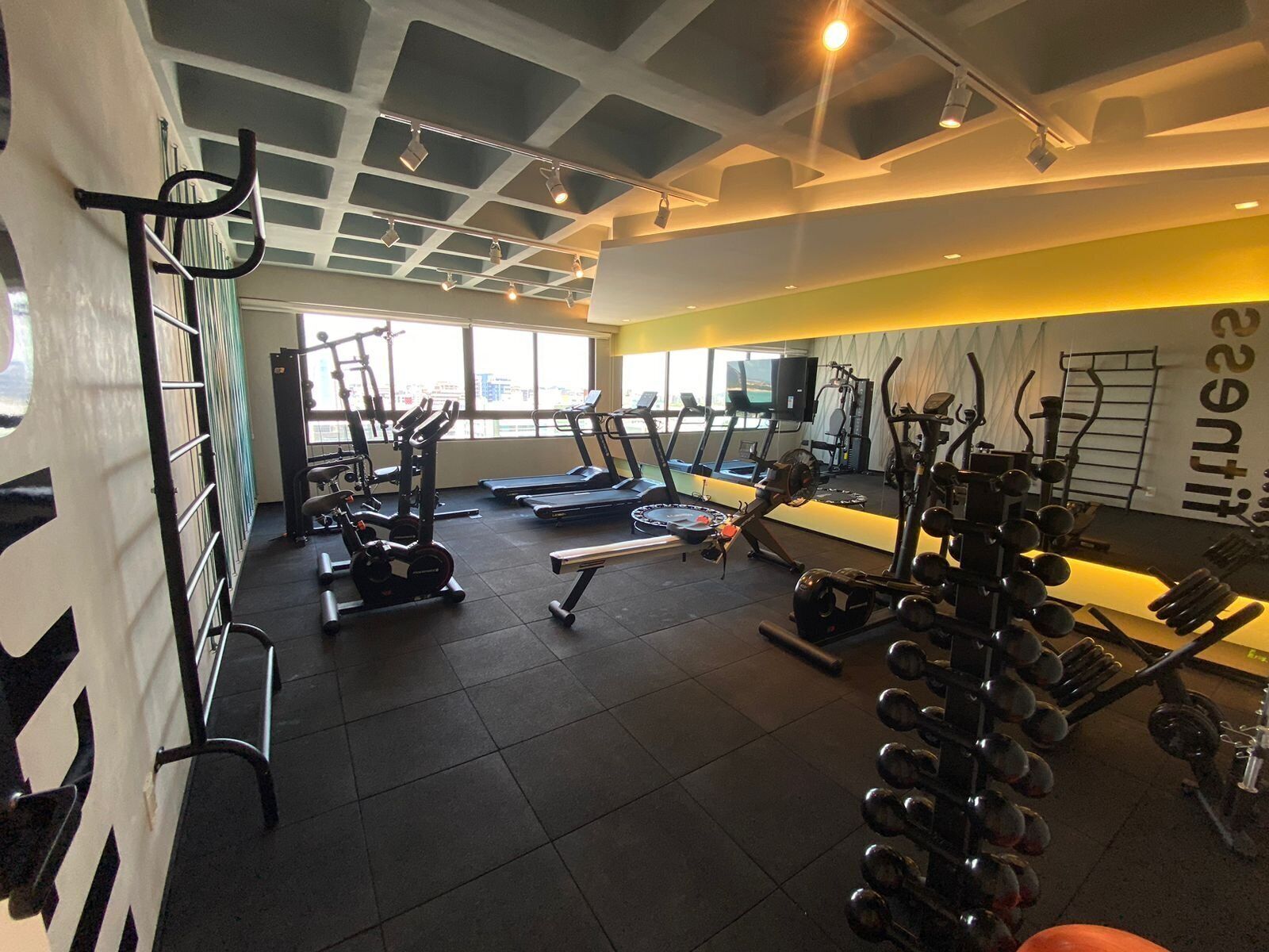A gym with various exercise equipment, including treadmills, weight machines, and free weights.