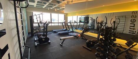 A gym with various exercise equipment, including treadmills, weight machines, and free weights.