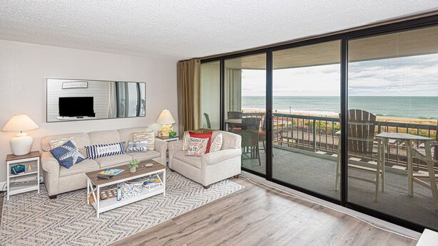 Ein modernes Wohnzimmer mit einer großen Schiebeglasdoor zum Balkon mit Meerblick.