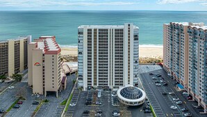 Ein Hochhaus-Hotel mit einem zentralen Atrium, einem Parkplatz und Blick auf Strand und Meer.