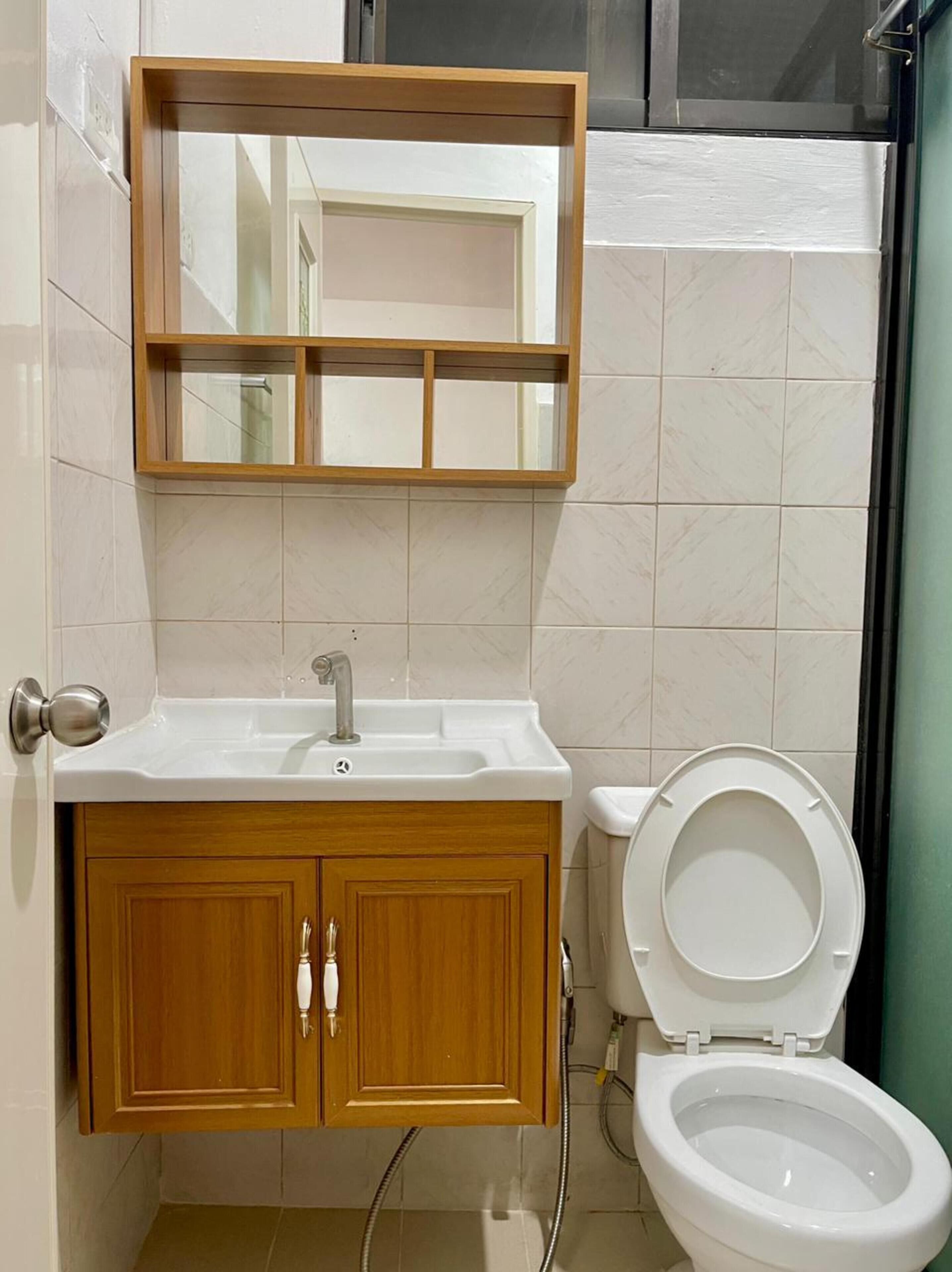 Une salle de bain avec un meuble-lavabo en bois, un évier et des toilettes.