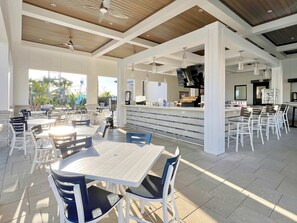 A spacious indoor dining area with multiple tables and chairs, a counter with a coffee station, and a ceiling fan.
