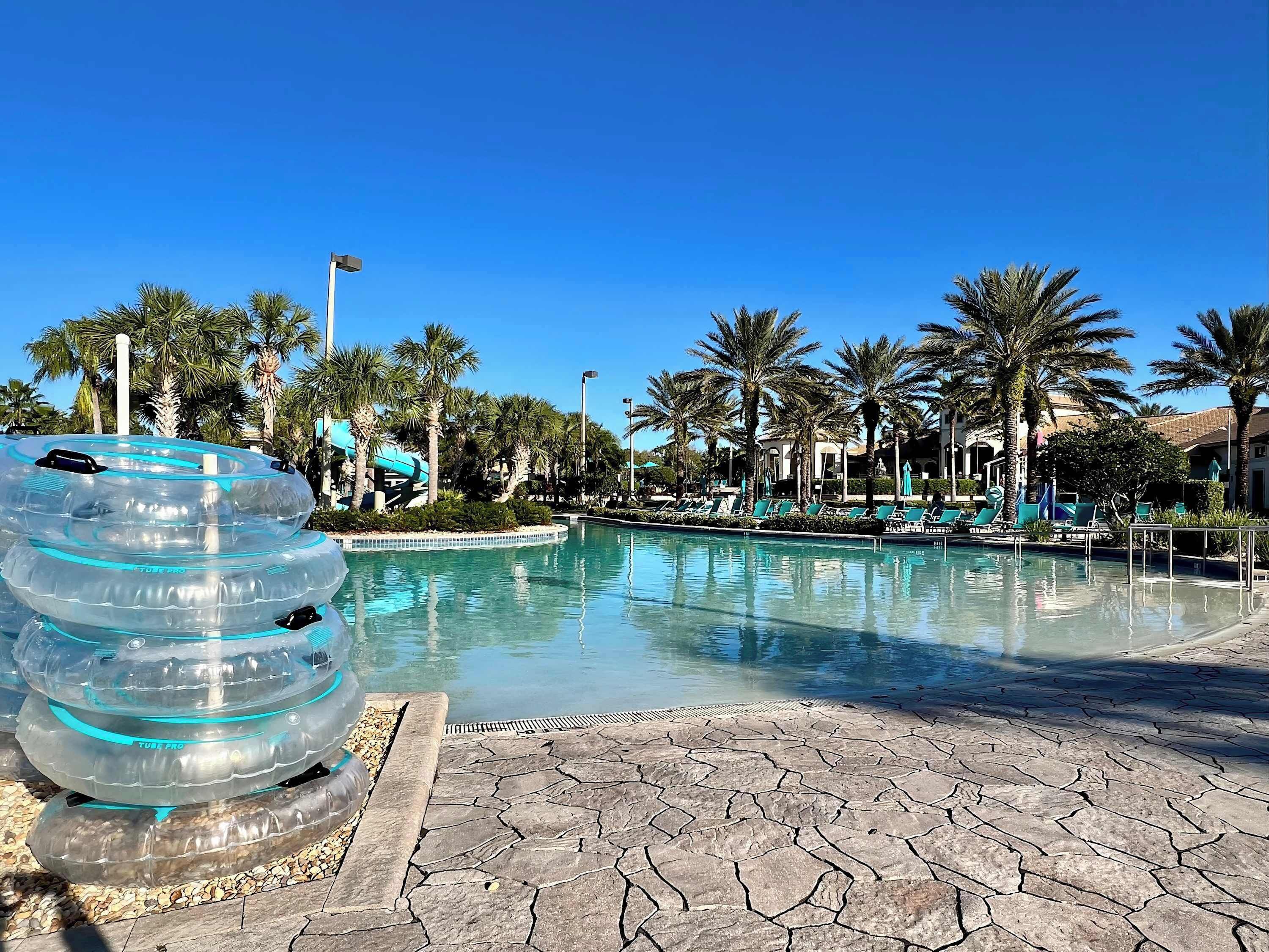A pool area with clear blue water, surrounded by palm trees and lounge chairs.