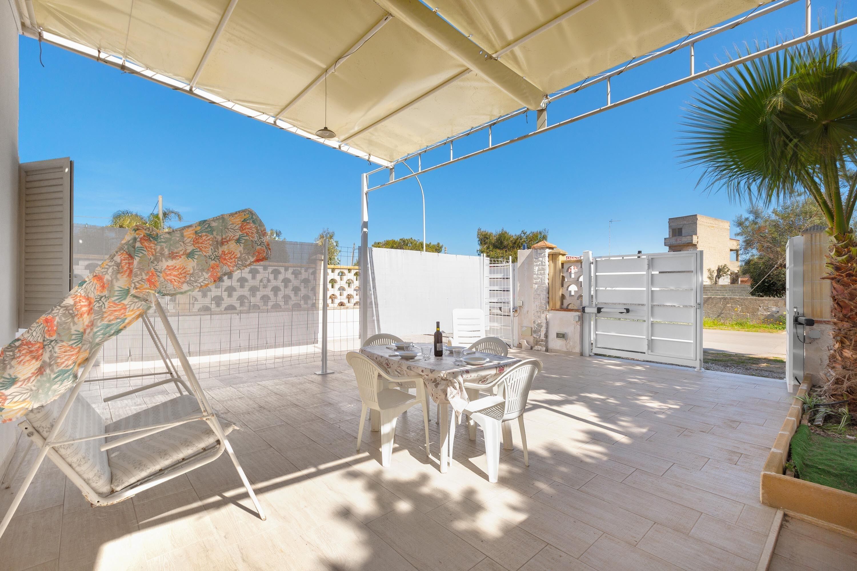 An outdoor patio with a table and chairs, a swing, and a covered area.