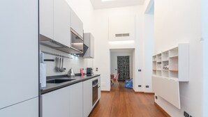 A modern kitchen with white cabinets, a black countertop, and a wooden floor. - Elegant Home With Sauna by Wonderful Italy (Turin)