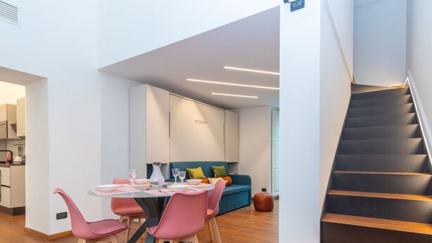 A modern interior with a dining area, a sofa, and a staircase. - Elegant Home With Sauna by Wonderful Italy (Turin)
