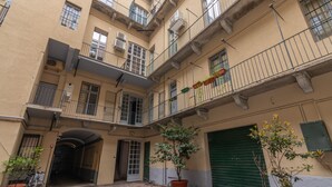 A courtyard with a potted tree, a bicycle, and a green shutter door. - Elegant Home With Sauna by Wonderful Italy (Turin)