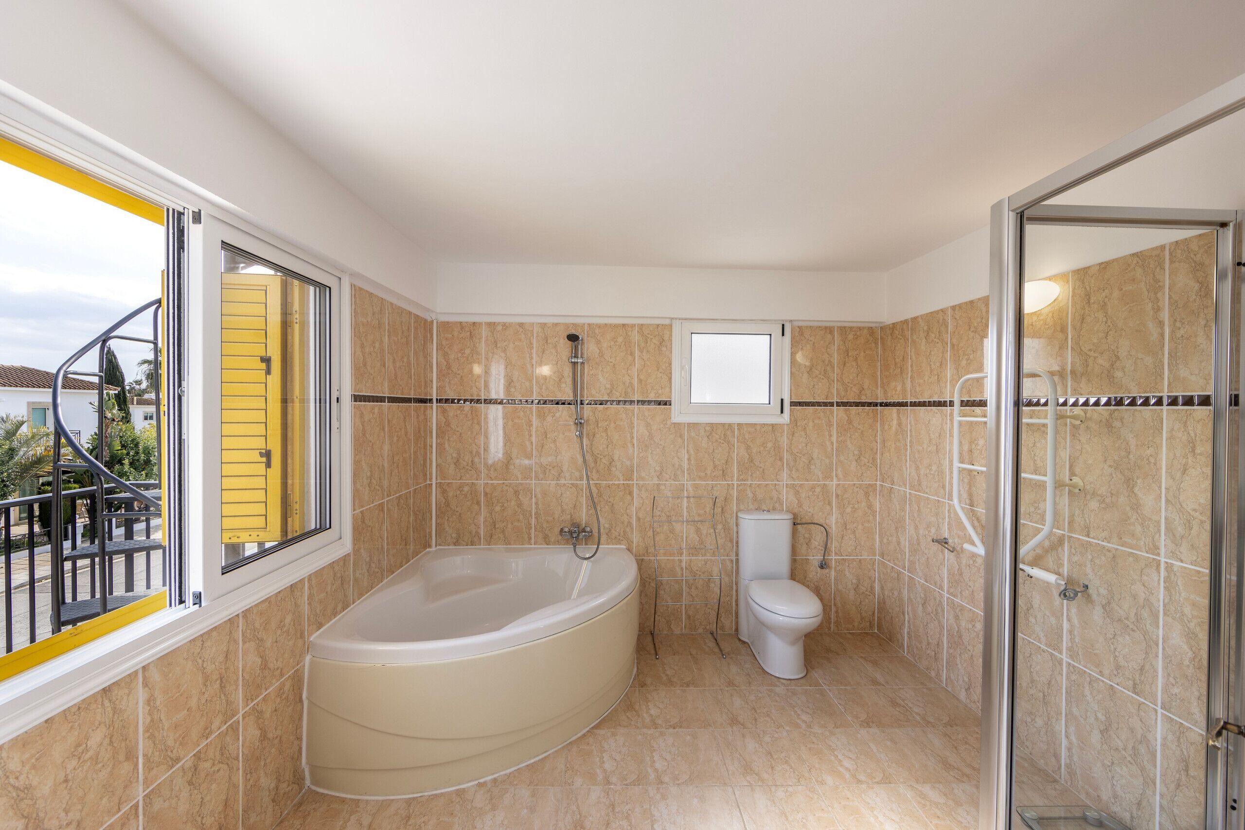 A modern bathroom with a bathtub, toilet, and glass shower enclosure.