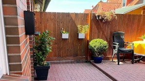 Un espace patio avec un sol en briques, une clôture en bois et des plantes en pot.