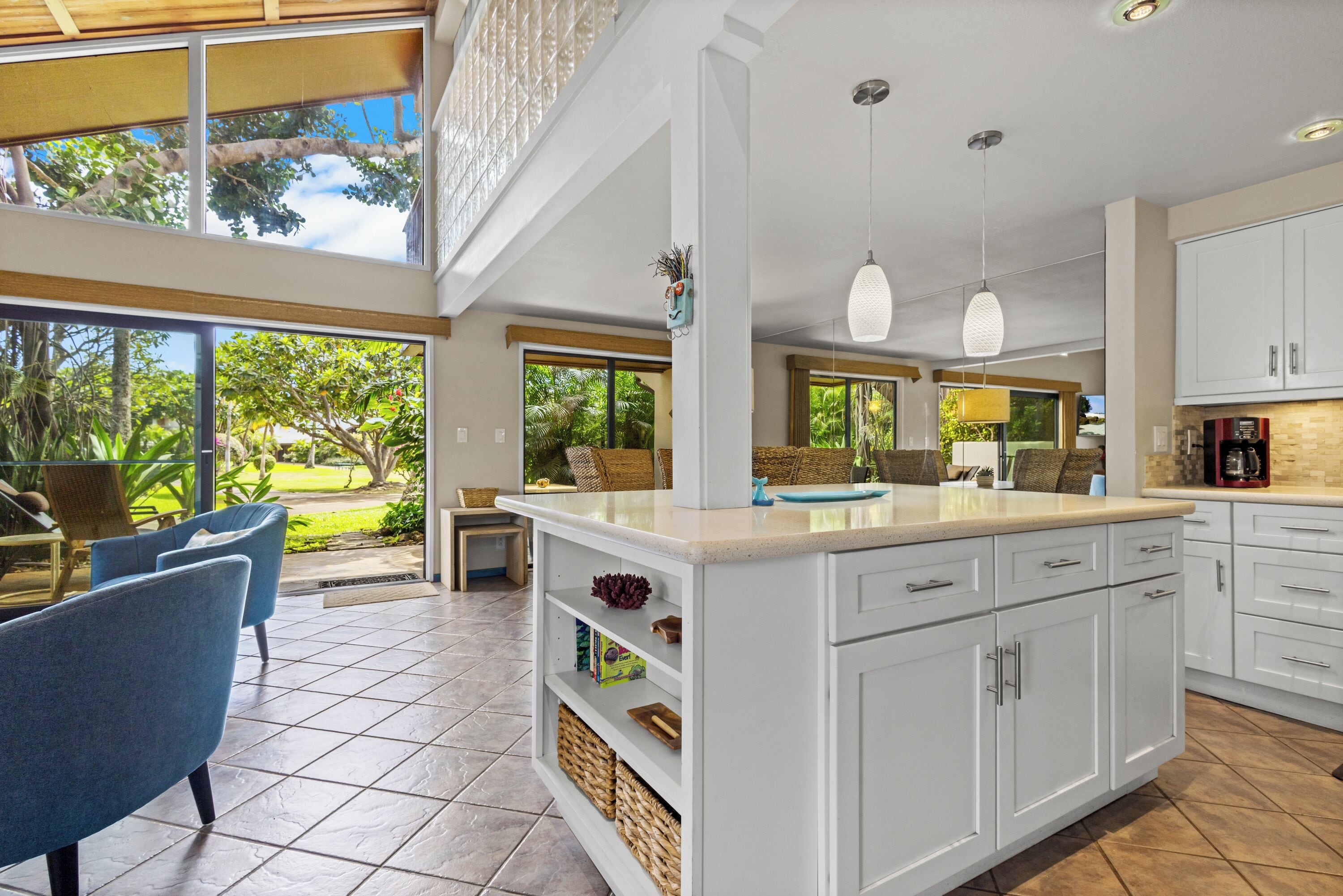 Una cocina moderna con armarios blancos, una isla grande e iluminación colgante.