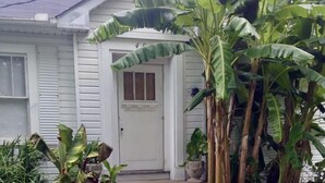 A house with a front porch, a concrete pathway leading to the door, and various potted plants. - Garden Cottage in the city. (West Monroe)