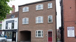 A two-story brick building with a red door and multiple windows. - Cattle Market View Apartment (Boston)