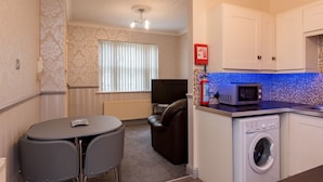 A compact living space with a dining area, a sofa, a washing machine, and a microwave. - Cattle Market View Apartment (Boston)