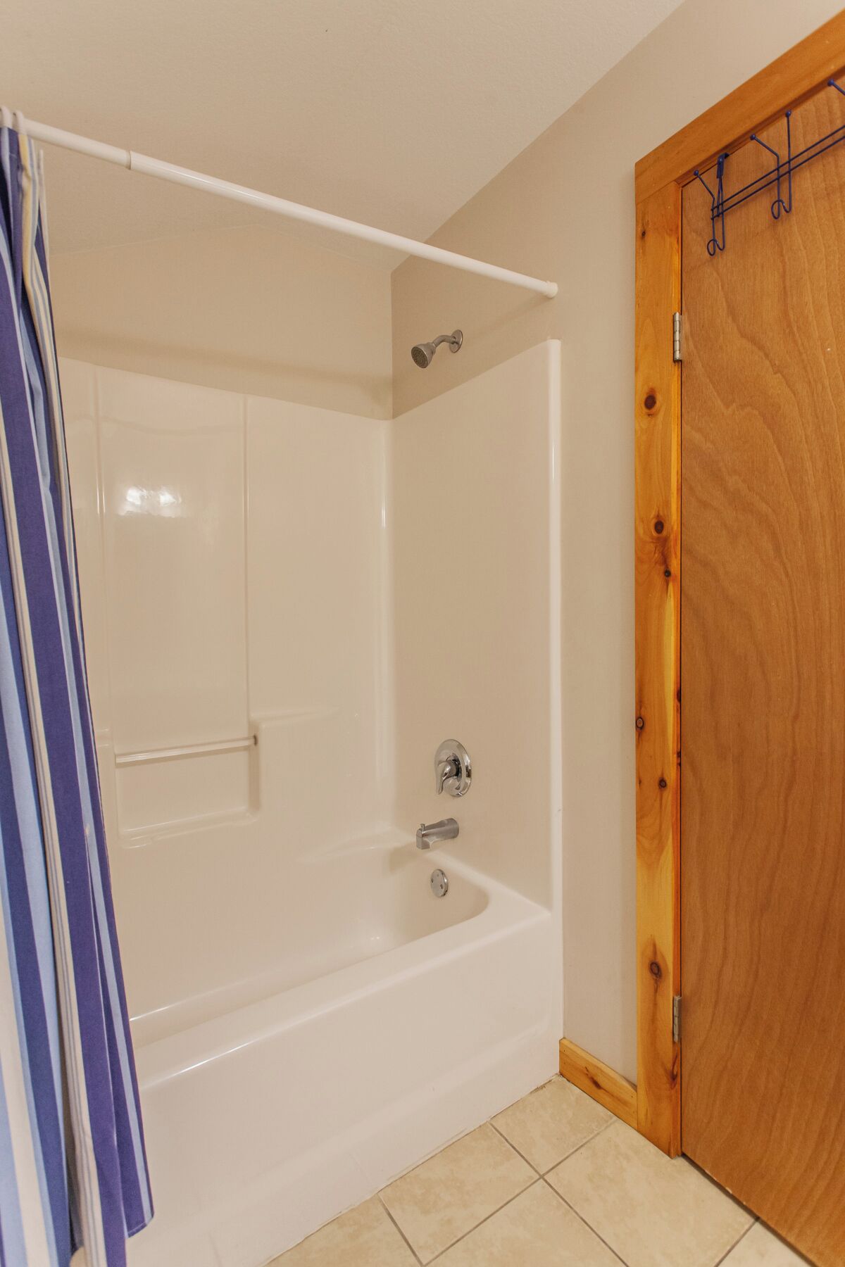 Ein Badezimmer mit einer weißen Badewanne, einer Dusche und einer Holztür.
