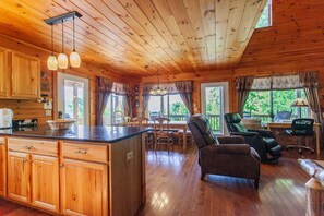 A wooden cabin interior with a kitchen, dining area, and seating space. - Escape to Goldies Hideaway (Bryson City)