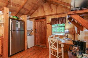 A wooden cabin kitchen with a refrigerator, stove, and dining table.