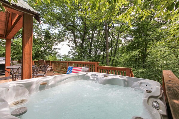 A hot tub on a wooden deck surrounded by trees.