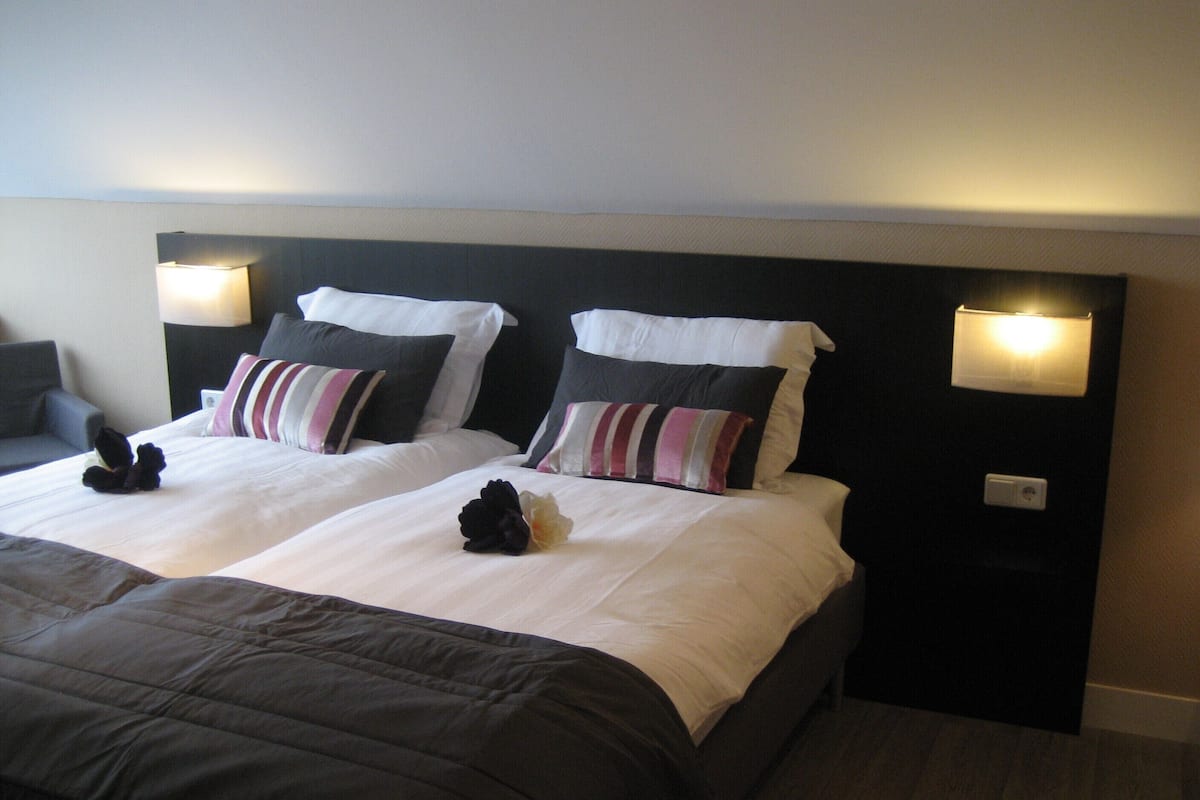 A double bed with a dark headboard and two bedside lamps.