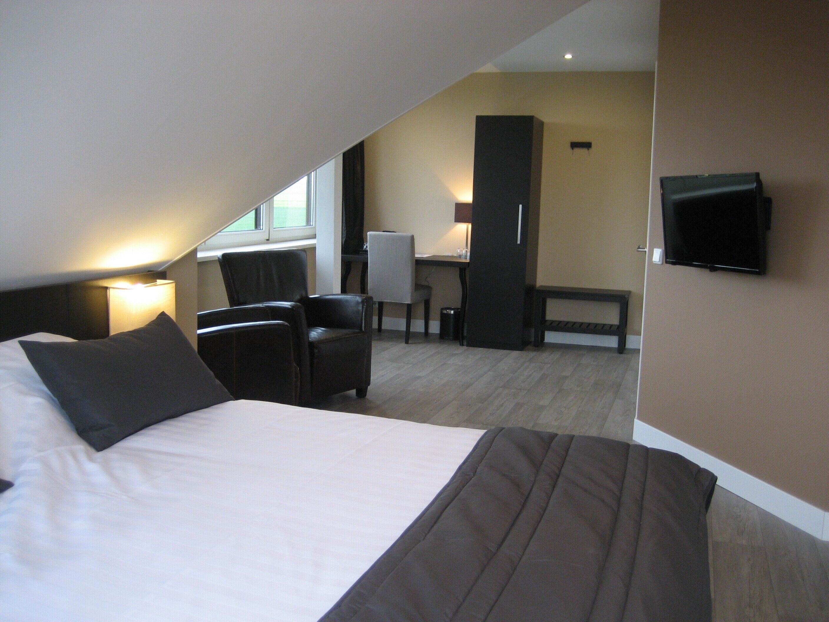 Ein Hotelzimmer mit Bett, Schreibtisch, Stuhl und Fernseher.