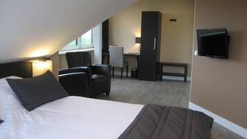 Ein Hotelzimmer mit Bett, Schreibtisch, Stuhl und Fernseher.