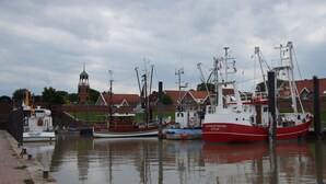 A harbor with several boats docked, a clock tower, and buildings in the background. - Bed & Breakfast Rheiderland (Bunde)