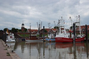 A harbor with several boats docked, a clock tower, and buildings in the background.