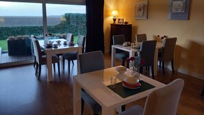 A dining area with a table set for four, a lamp, and a view of the outdoors. - Bed & Breakfast Rheiderland (Bunde)