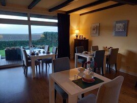 A dining area with a table set for four, a lamp, and a view of the outdoors.