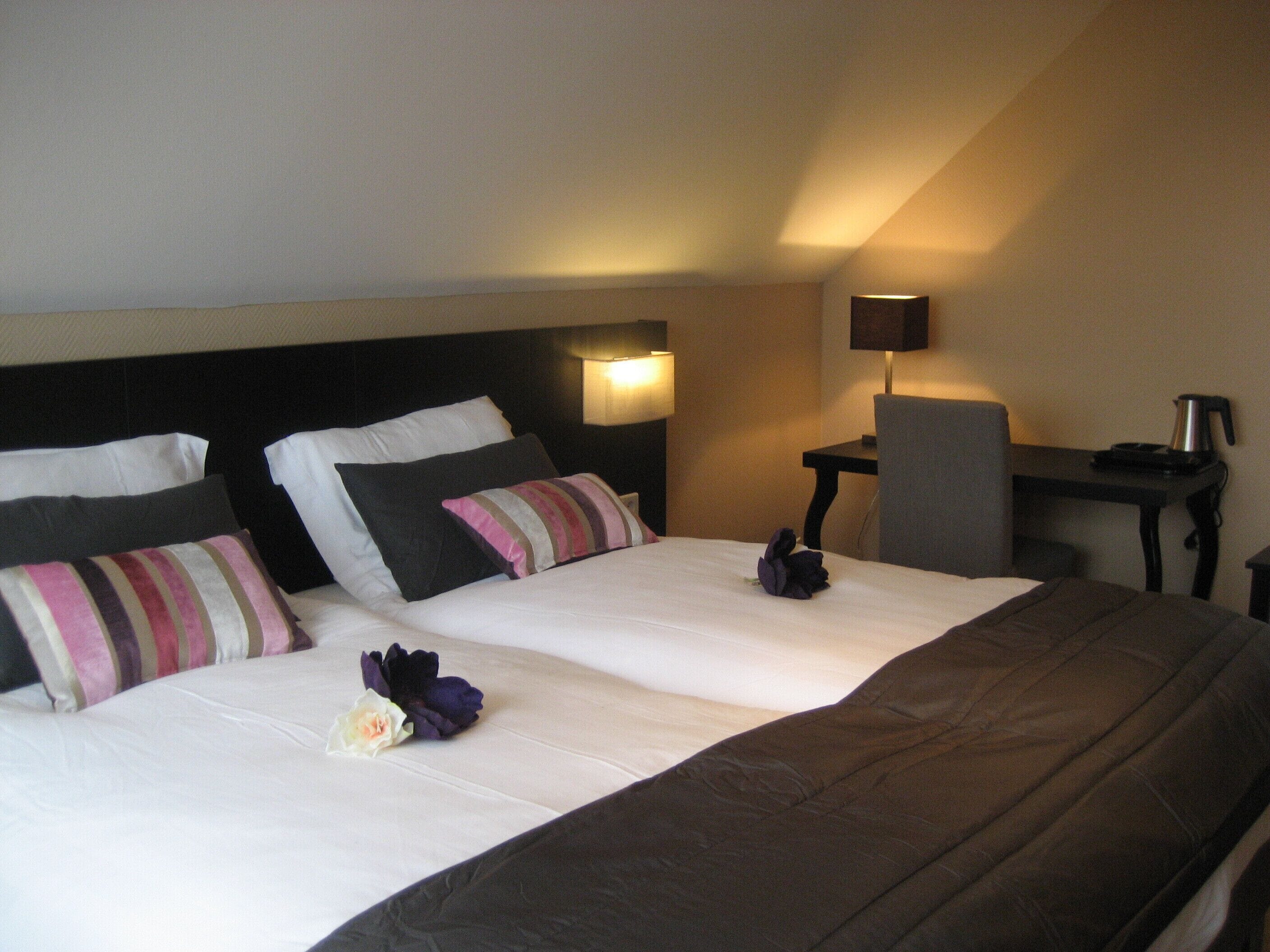A hotel room with a large bed, two bedside tables, a desk, and a chair.
