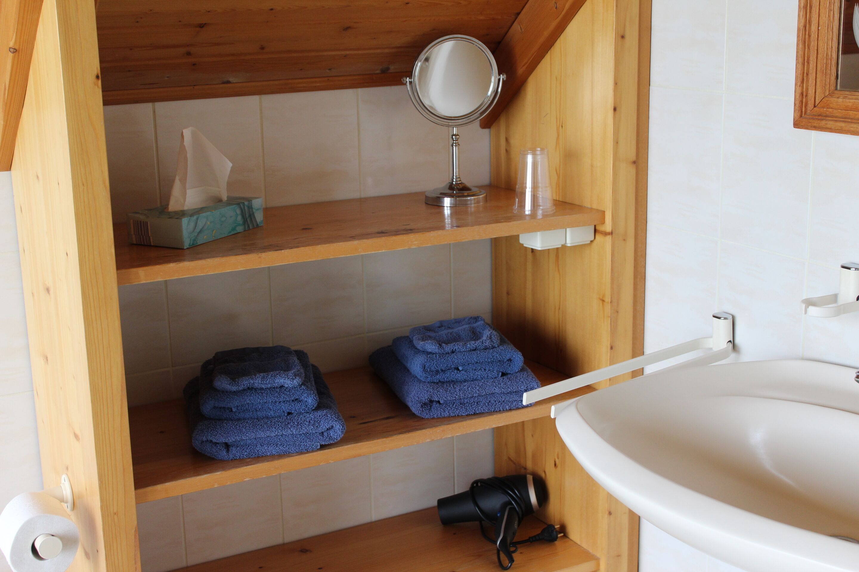 Une salle de bain avec des étagères en bois, un miroir, un lavabo et des serviettes.