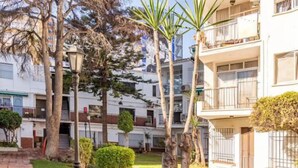 Um edifício residencial com vários andares, varandas, um jardim bem cuidado e um poste de luz.