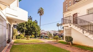 Um pátio com gramado bem cuidado, uma escadaria e uma palmeira.