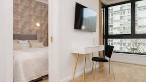 Un dormitorio moderno con cama, escritorio y televisor.