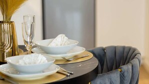 Una mesa de comedor con dos platos, un vaso y un jarrón con flores secas.