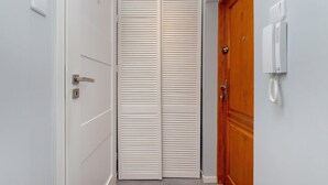 A narrow hallway with a white door on the left and a wooden door on the right. - Charming Studio with Balcony | Great Location in Gdynia (Gdynia)
