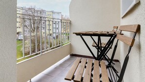 A balcony with a table and chairs, a view of apartment buildings, and a railing. - Charming Studio with Balcony | Great Location in Gdynia (Gdynia)