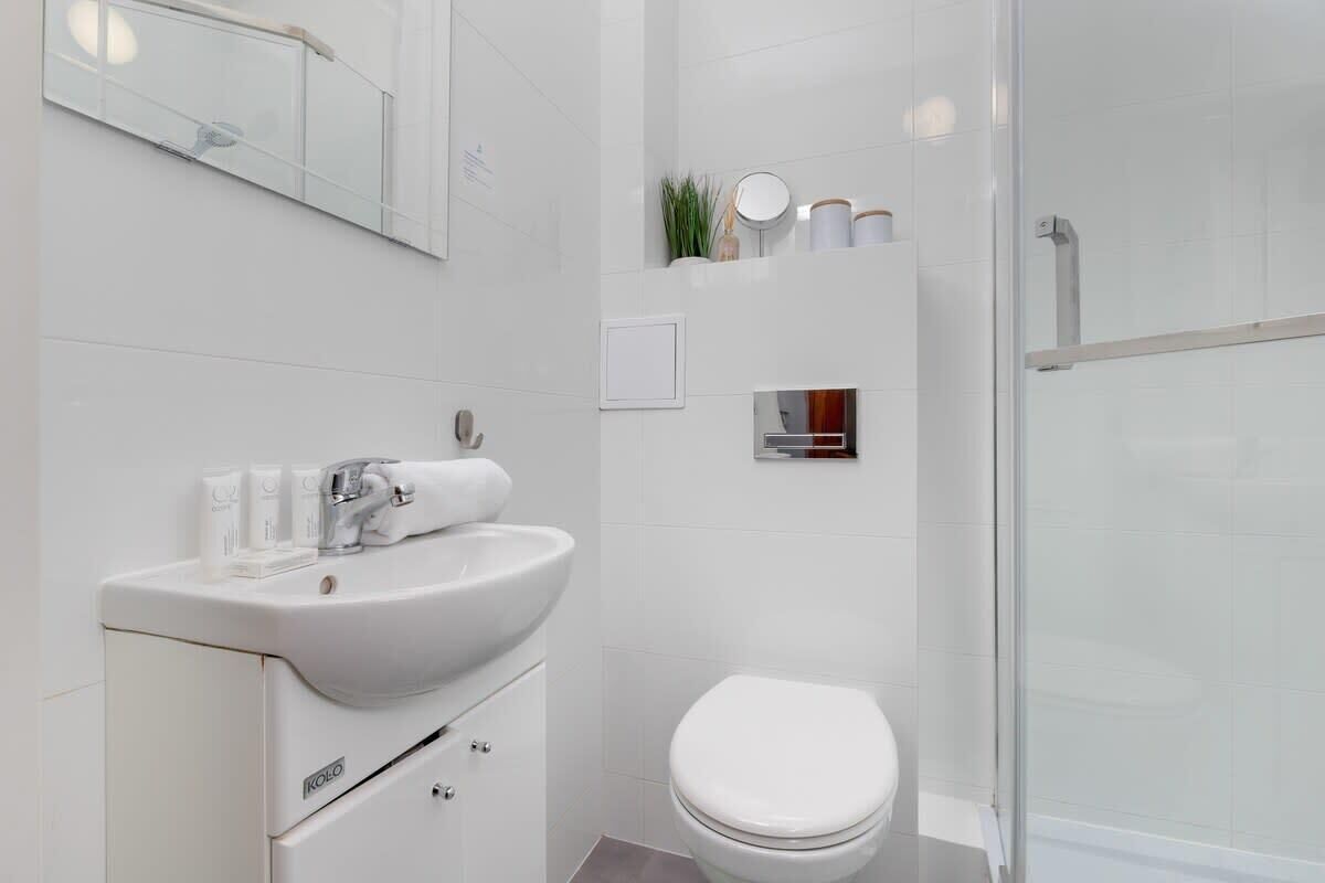 A modern bathroom with a white sink, mirror, and toilet.