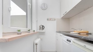 A modern kitchen with white cabinetry, a built-in oven, and a countertop with a kettle and a bread loaf. - Charming Studio with Balcony | Great Location in Gdynia (Gdynia)
