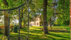 A lush garden with a wrought iron gate, a well-maintained lawn, and a building with a classic architectural style in the background. - Luxury Villa - Unesco Monferrato Langhe Roero with private pool (Asti)
