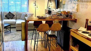 A cozy living room with a wooden dining table, two chairs, a sofa, and a TV. - Ridgeway Bed & Brksfst Suite, Full Kitchen, Slps 4 (Eureka Springs)