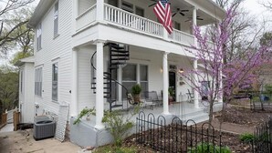A two-story house with a covered porch, a flag, and a fenced yard. - Ridgeway Bed & Brksfst Suite, Full Kitchen, Slps 4 (Eureka Springs)