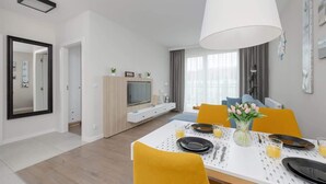 A modern dining area with a white table, yellow chairs, and a large white pendant light.