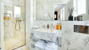 A modern bathroom with a glass-enclosed shower, a marble sink, and a large mirror. - The Lander - Serviced 3BR/3BA - Champs-Elysées (Paris)