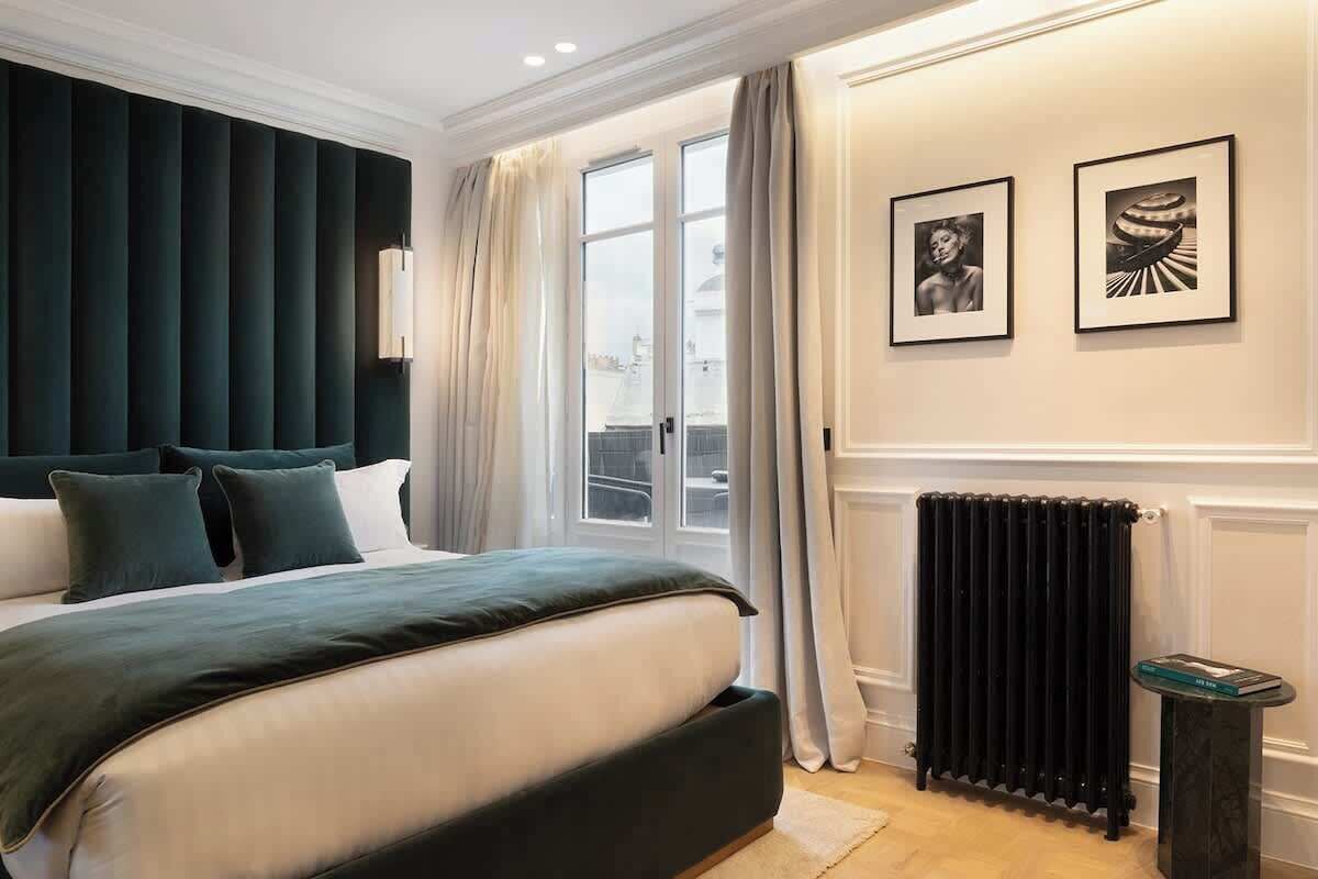 A bedroom with a large bed, a radiator, and two framed pictures on the wall.
