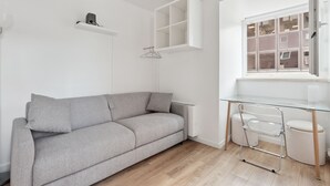 A modern, minimalist room with a grey sofa, a glass desk, and a white cabinet. - ID 412 - Beaugrenelle / rue Gaston de Caillavet (studio) (Paris)